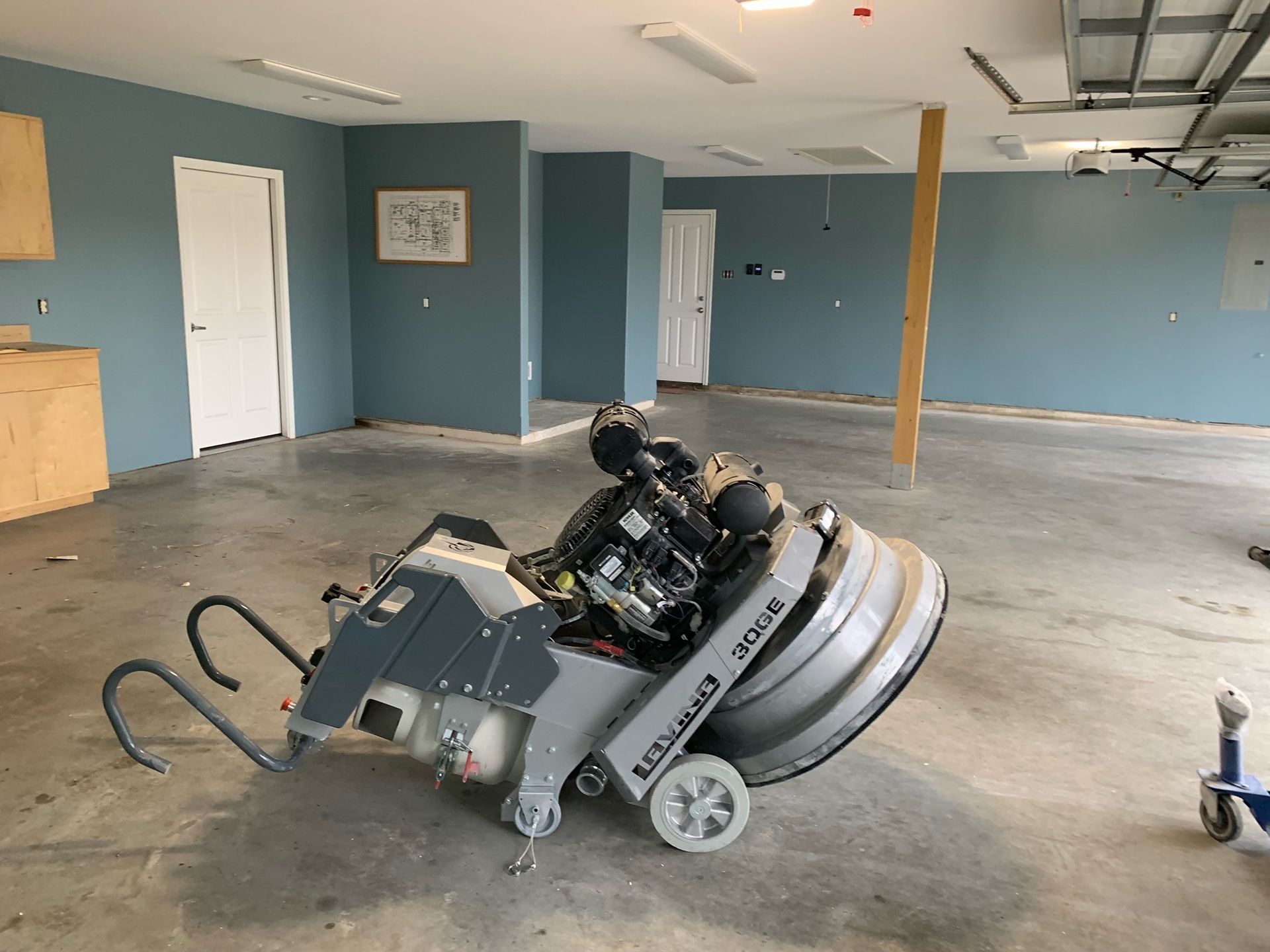 Concrete floor grinder in a room with blue walls and white doors.
