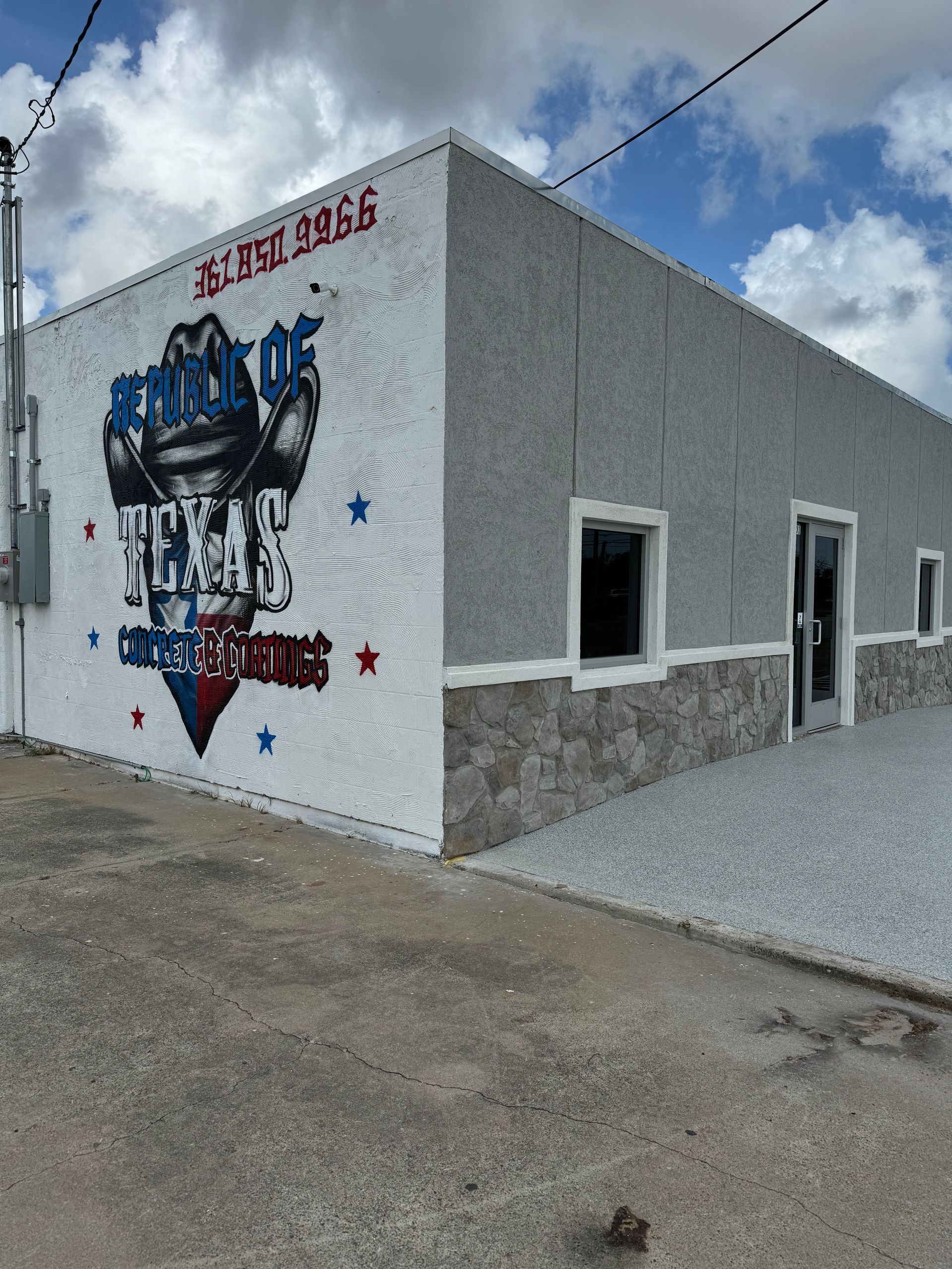 Gym exterior with mural on white wall, gray and stone trim, blue sky.
