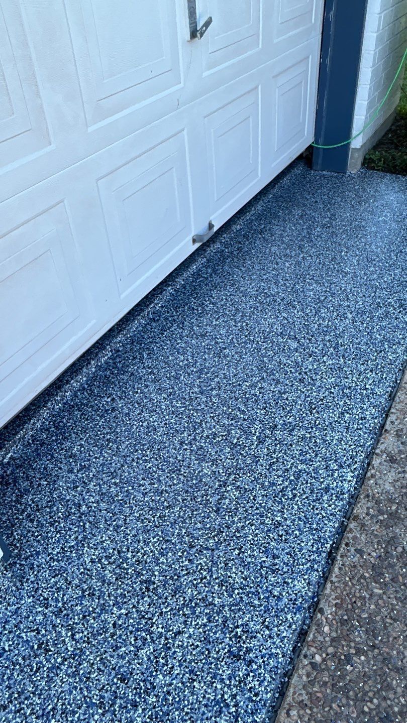 Blue speckled epoxy flooring in front of a white garage door.