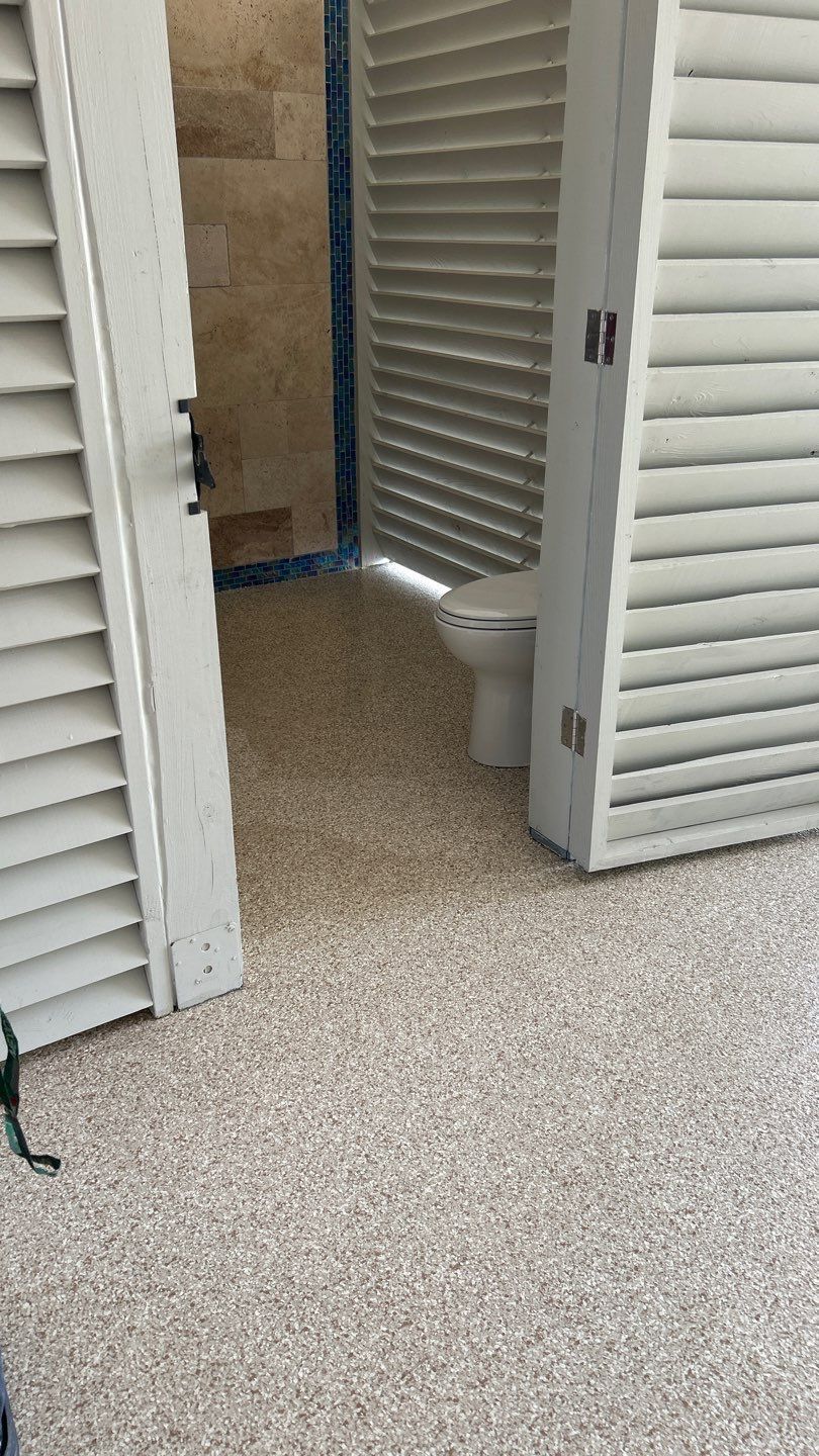 Open outdoor toilet with white shutter doors, gray floor.