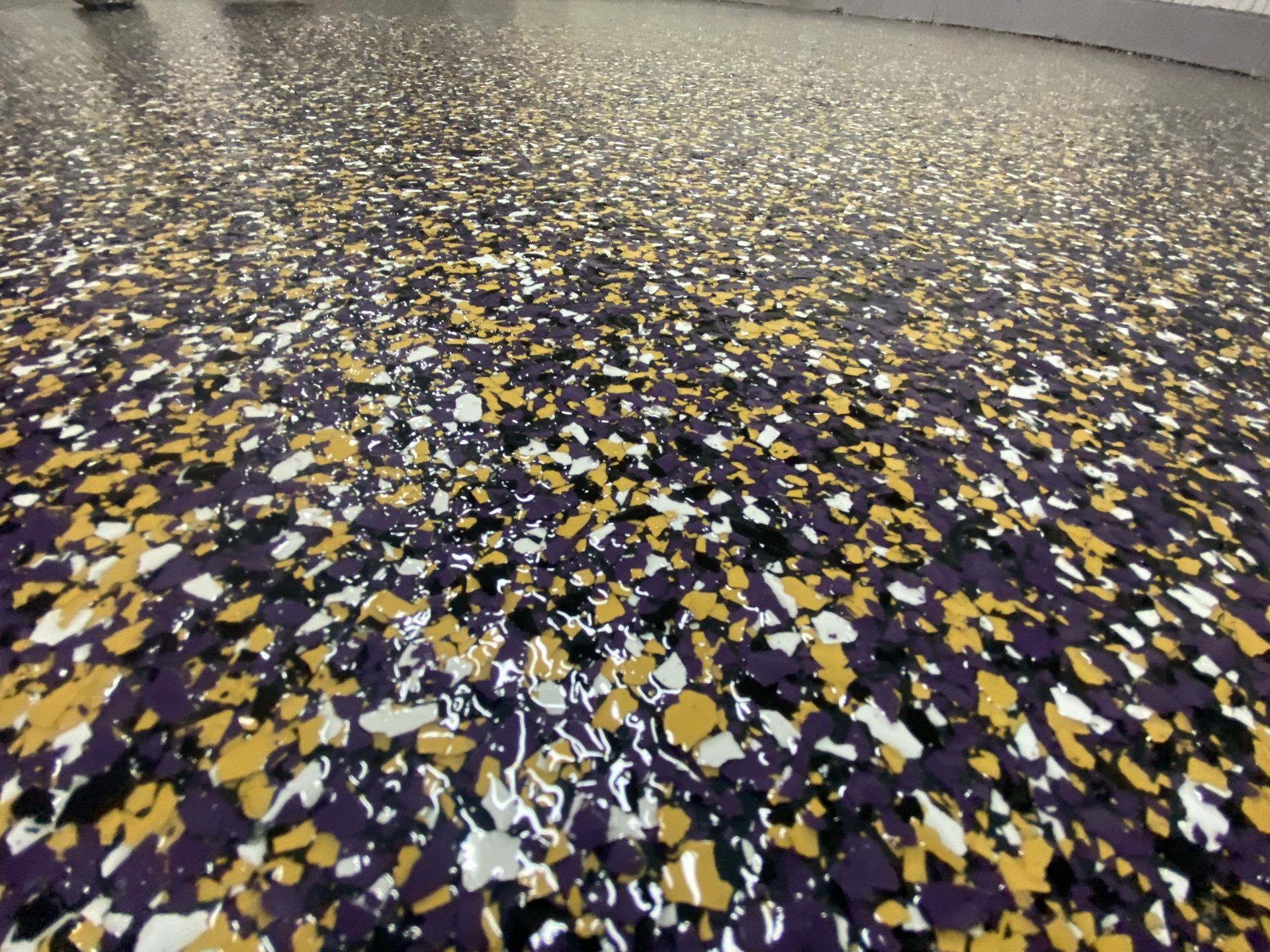Epoxy floor with scattered yellow, white, purple, and black flecks.