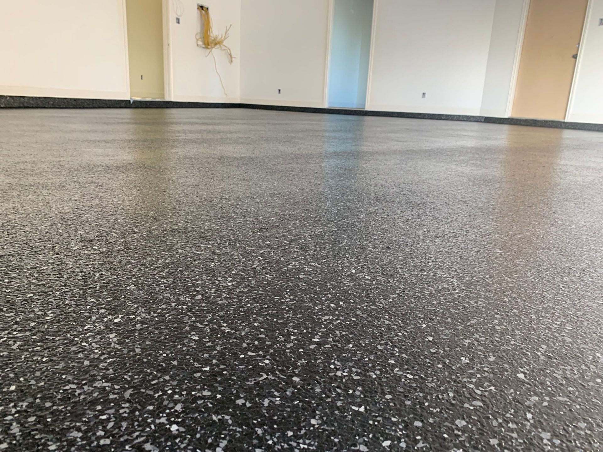 Dark, speckled epoxy floor in a room with white and pastel walls.