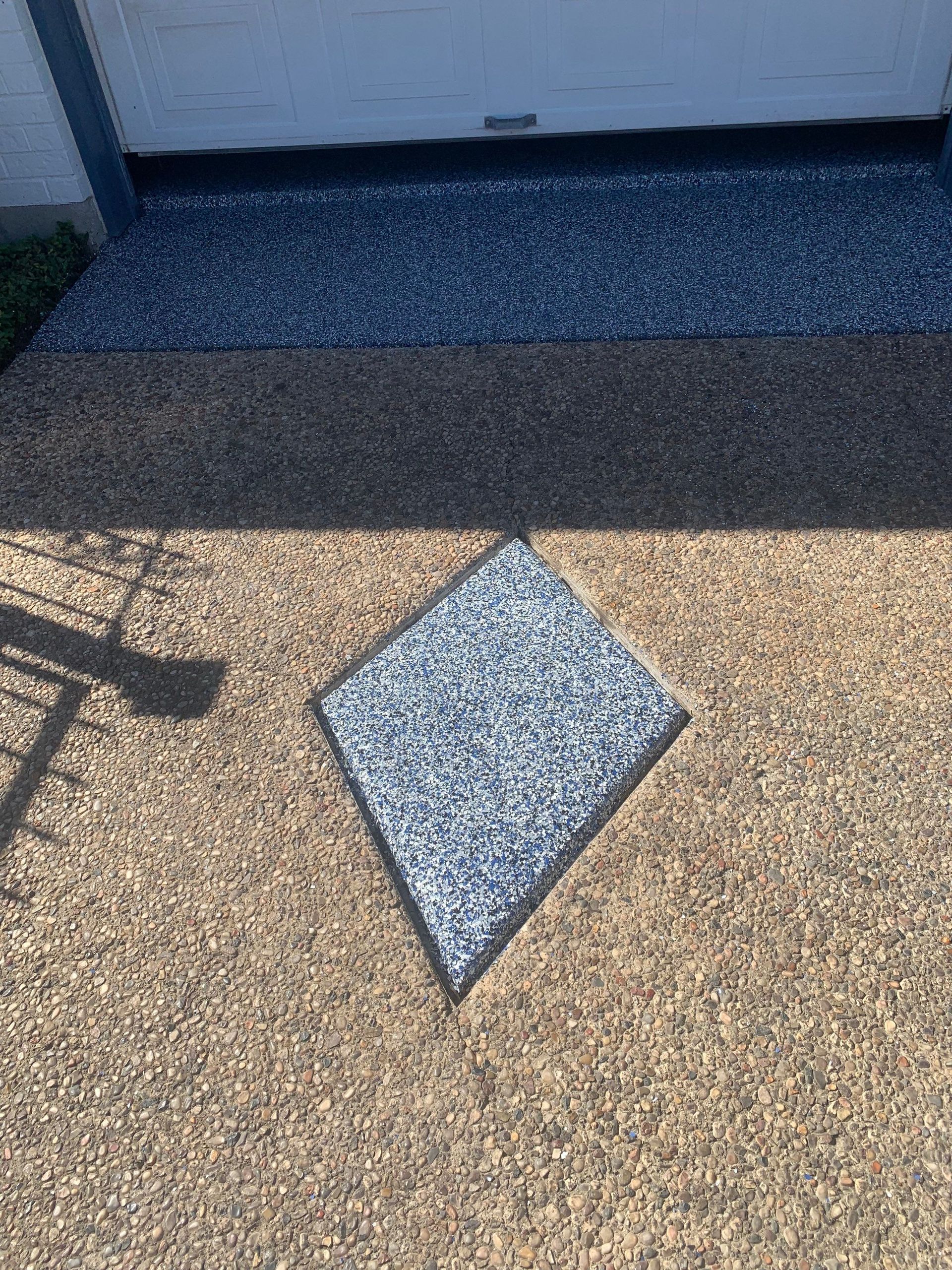 Diamond-shaped gray-speckled stone set into tan speckled ground, leading to a dark speckled entryway.