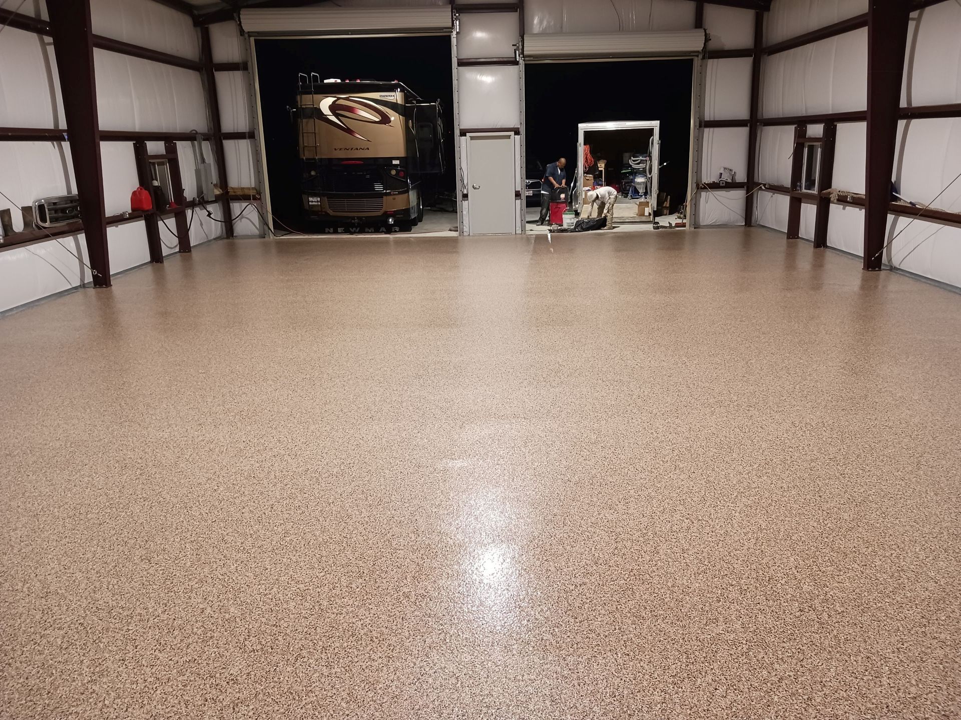 Spacious garage with epoxy flooring; RV parked inside, lights on.