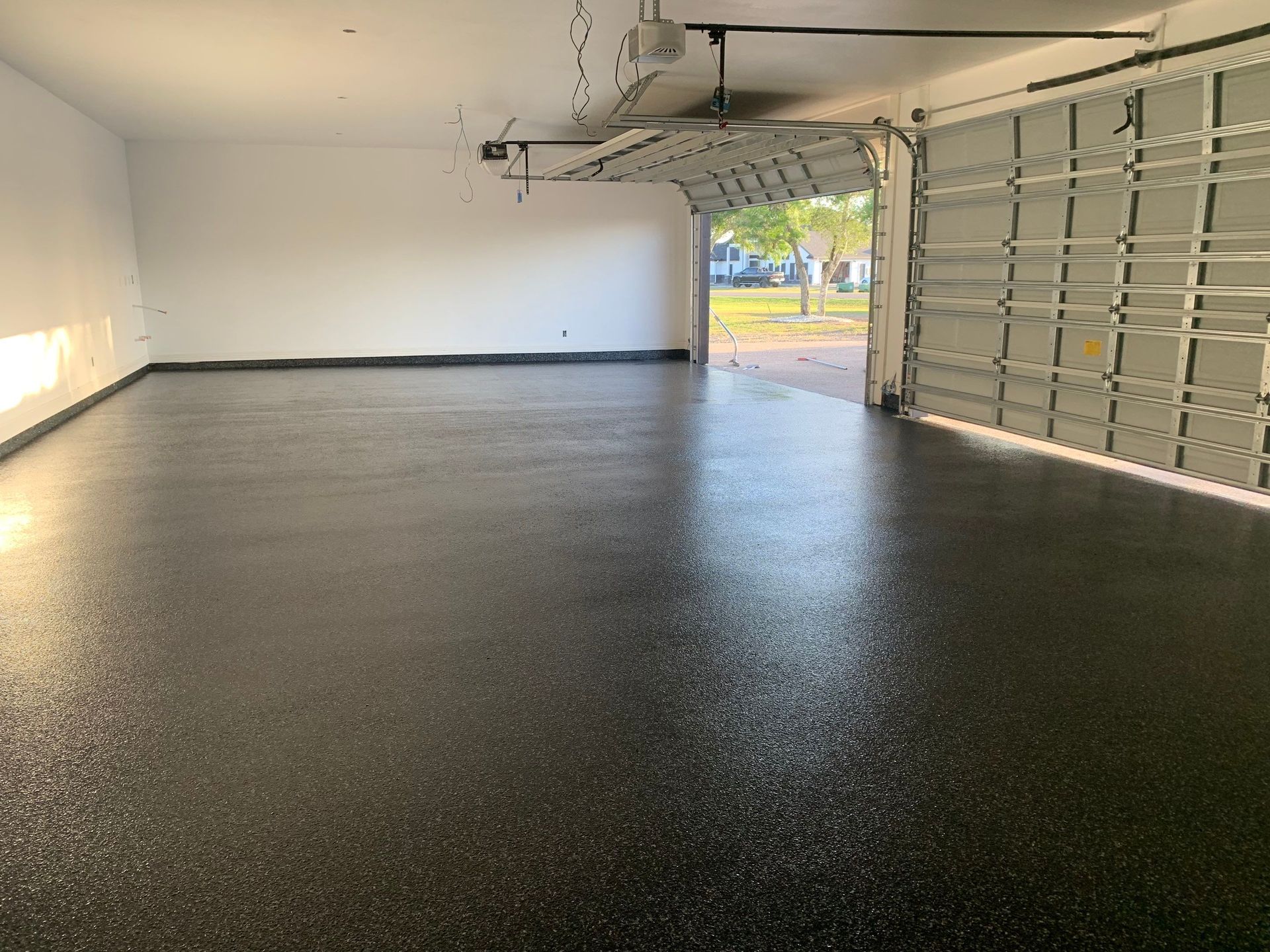 Black epoxy coated garage floor with open garage door.