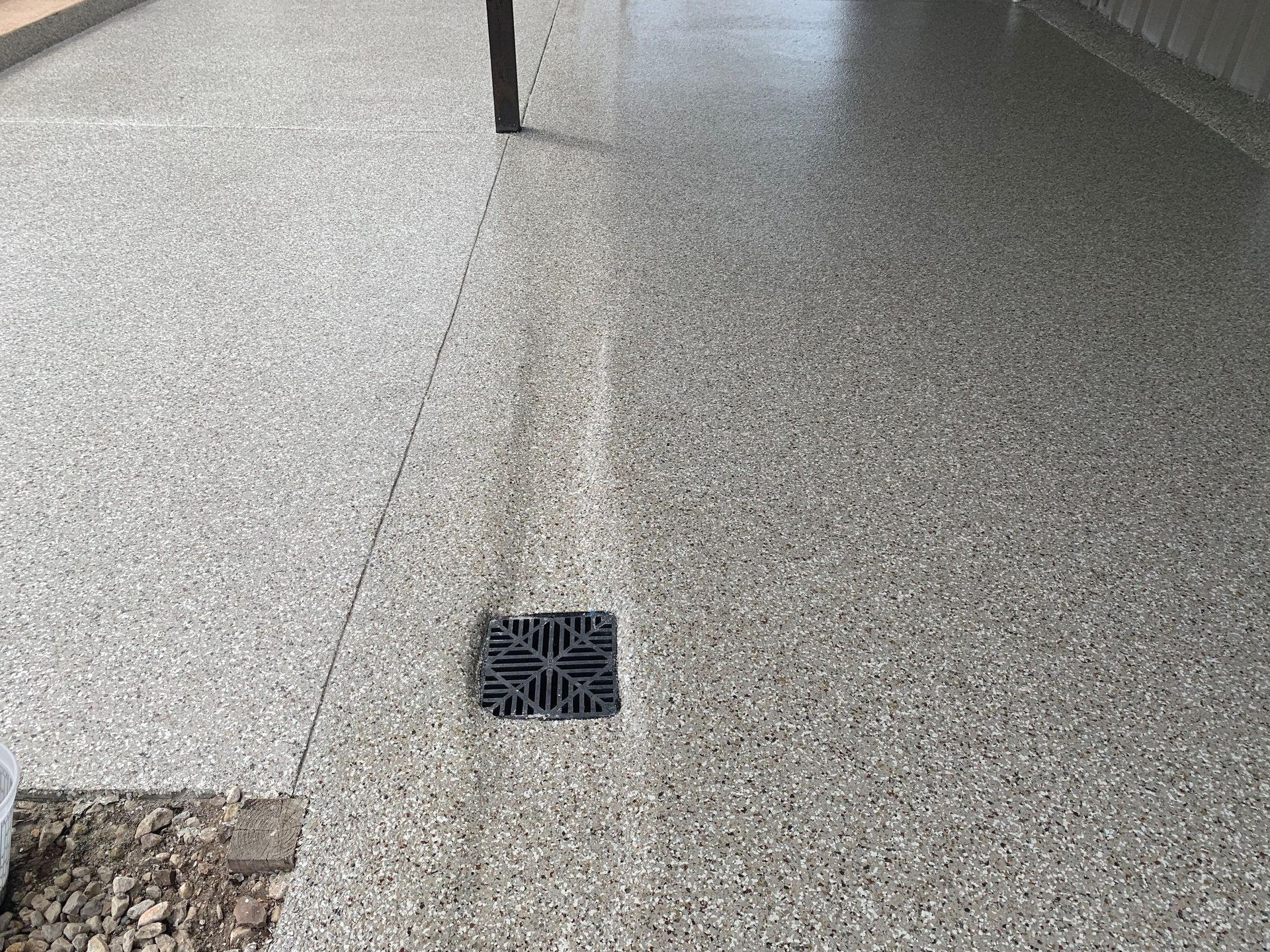 Gray speckled concrete floor with a black drain.