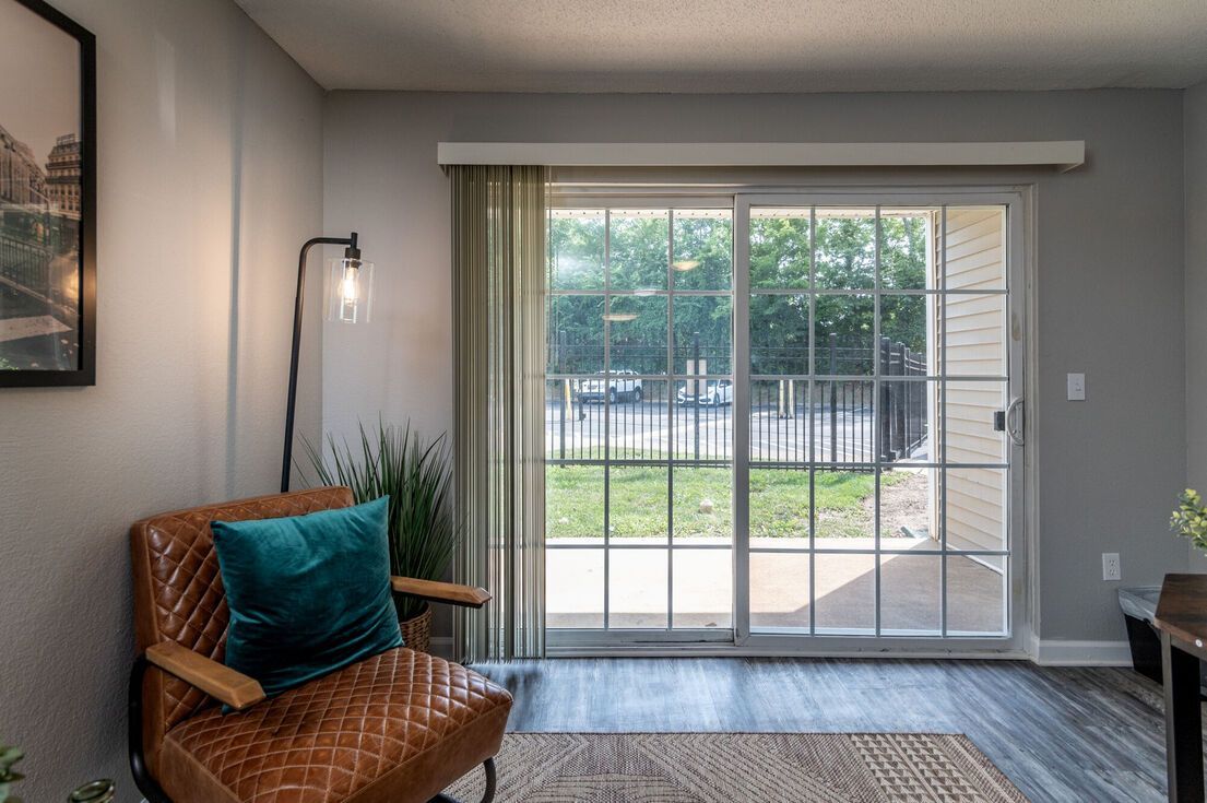 Cozy room with a brown leather chair, turquoise pillow, sliding glass door, and outdoor view.
