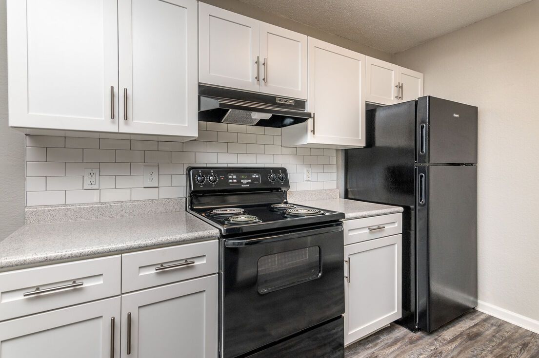 Modern kitchen with white cabinets, black appliances, and gray countertops.