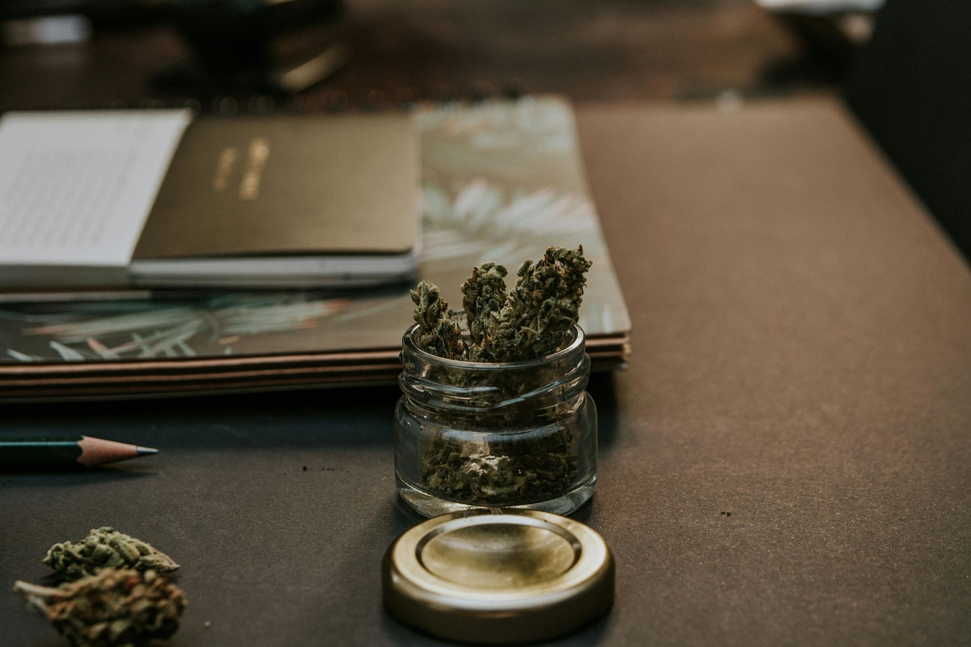 jar of cannabis on a desk with notepad