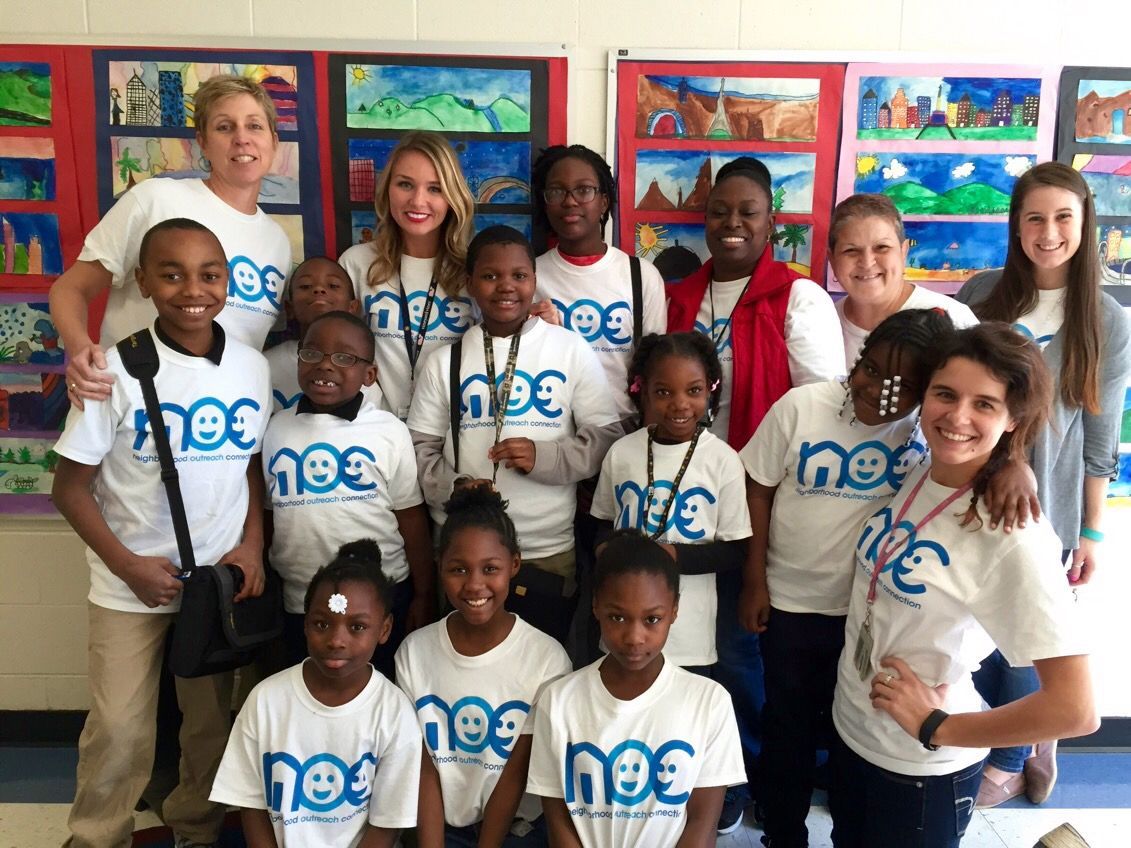 A person's hand reaching into a cardboard box filled with fresh green vegetables.