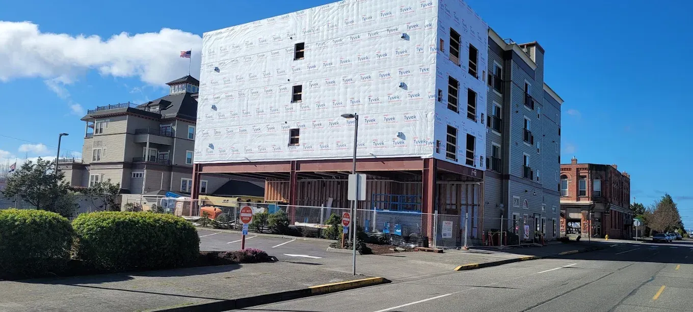 Buildings on a city street under a blue sky, with some under construction.