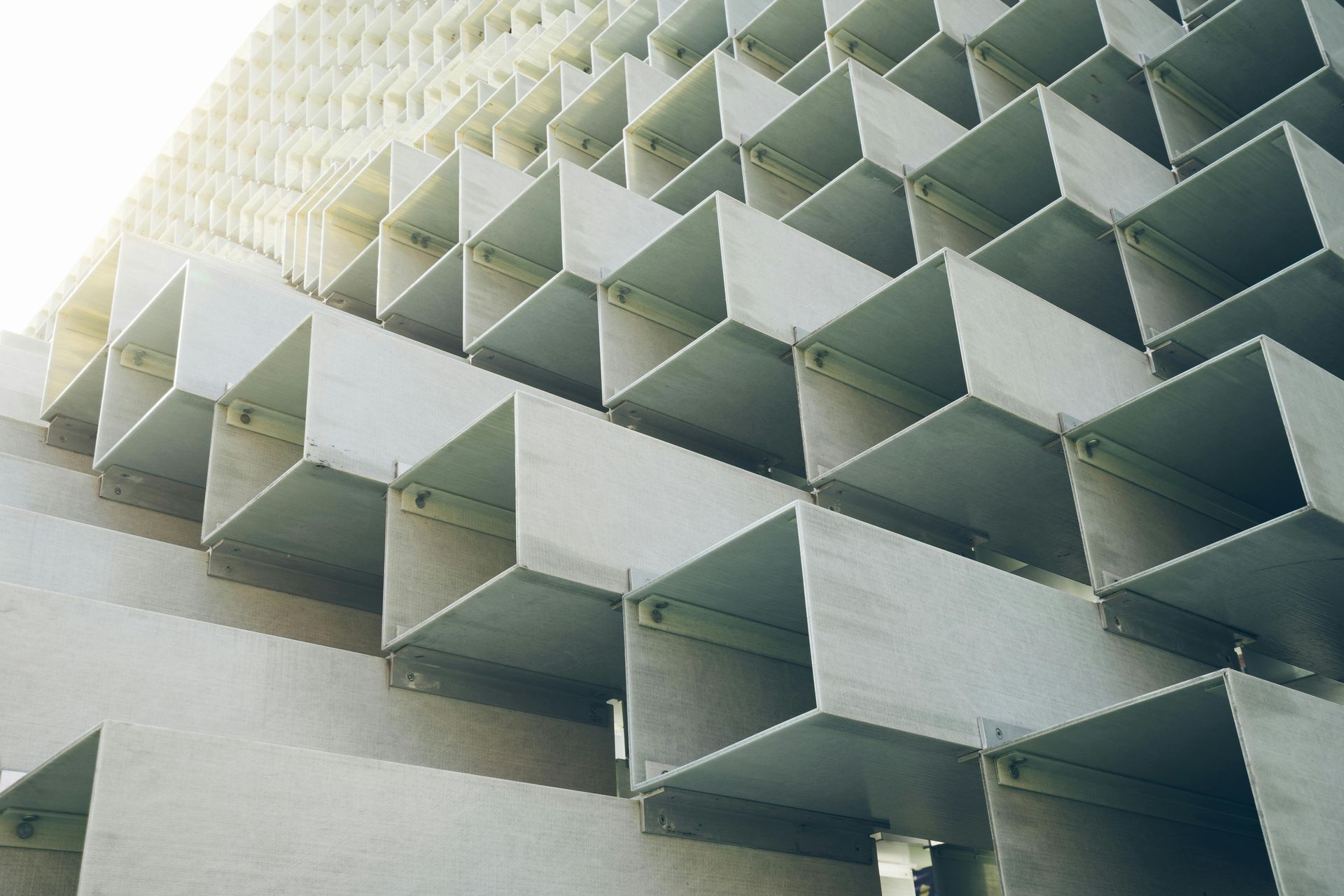 Exterior wall composed of stacked, metallic, angled cube-like structures, creating a repeating pattern.