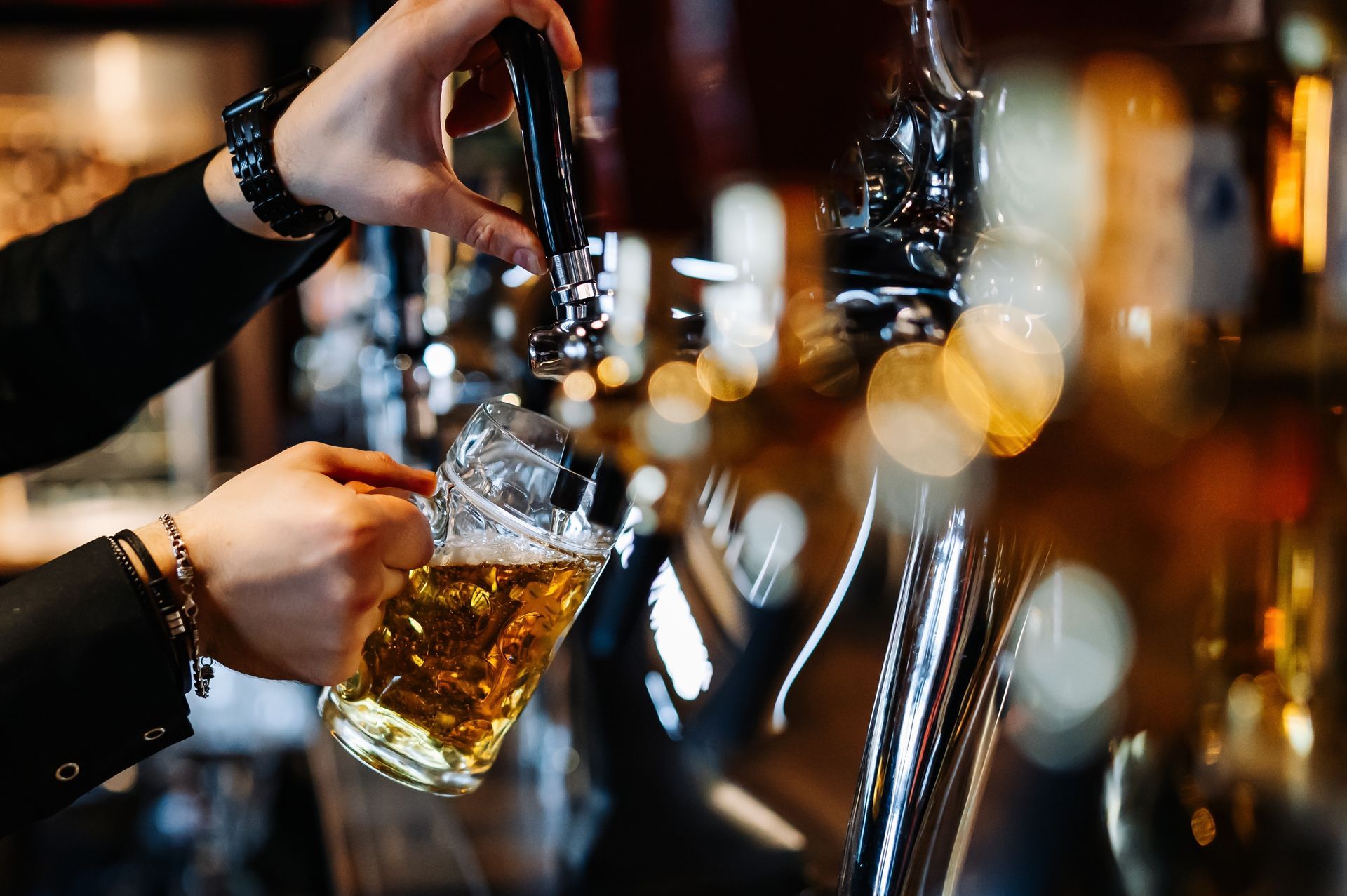 A bartender is pouring beer into a glass at a bar.