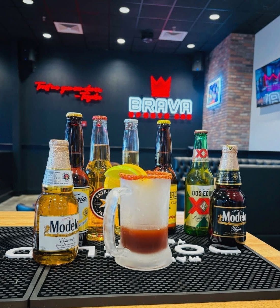 A group of young people are sitting at a bar drinking beer and orange juice.