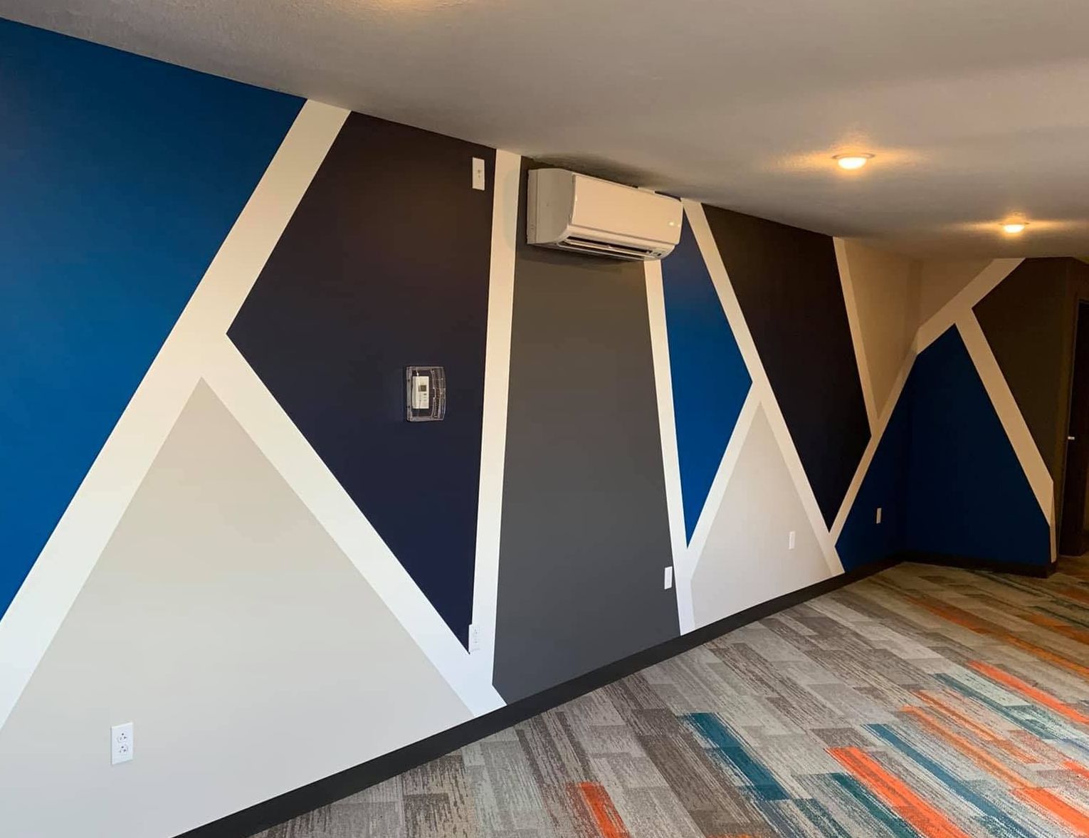 A room with a geometric pattern on the wall and a ceiling fan.