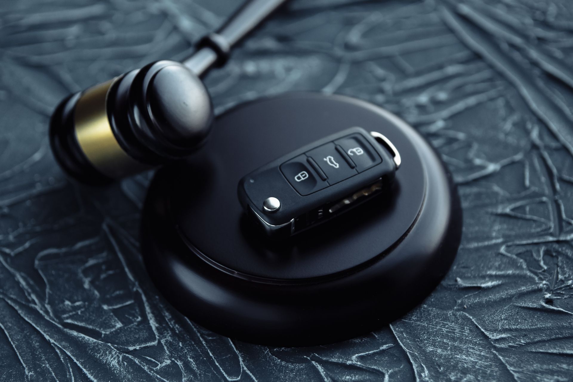 A car key is sitting on top of a judge 's gavel.