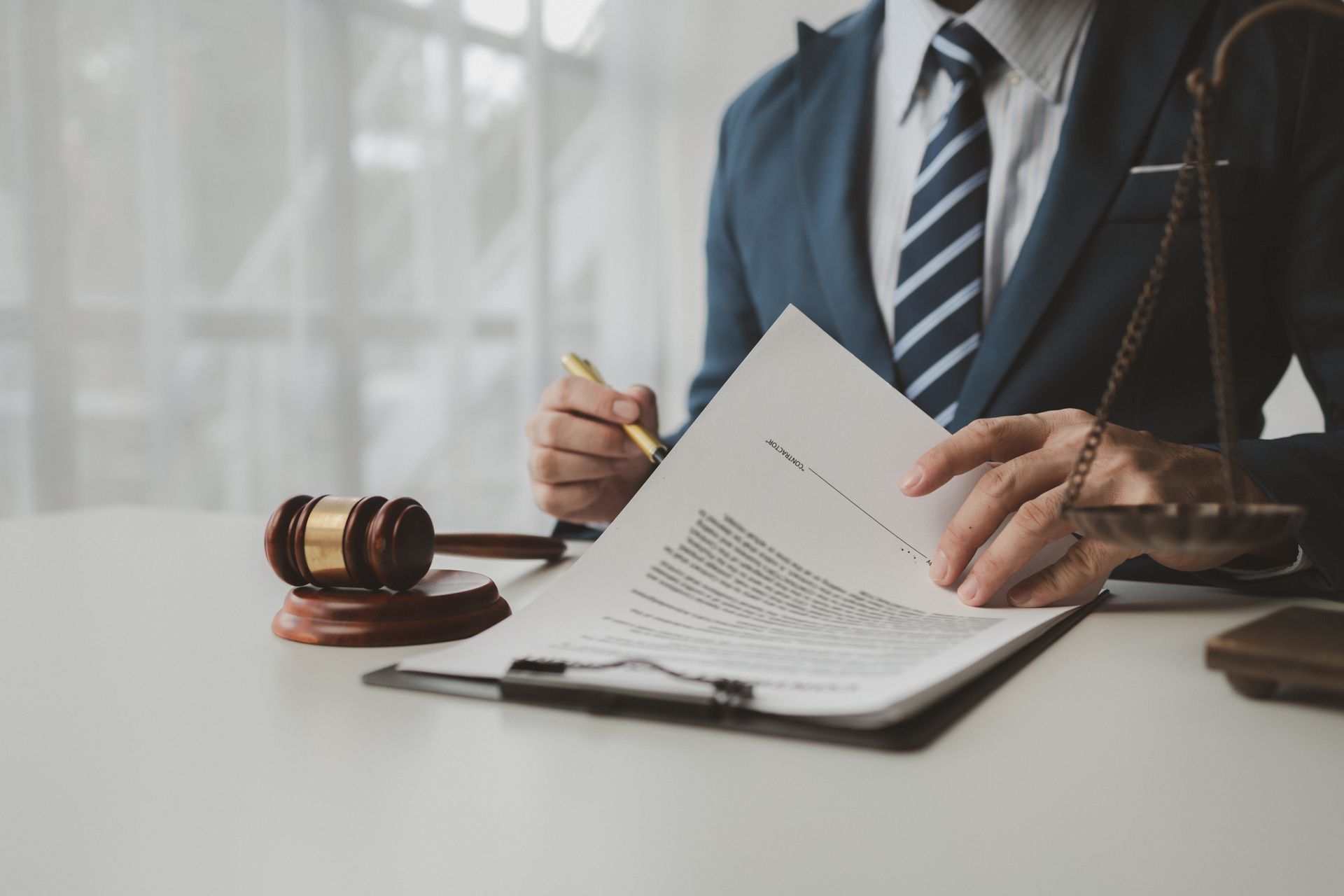 A man in a suit and tie is sitting at a table writing on a piece of paper.