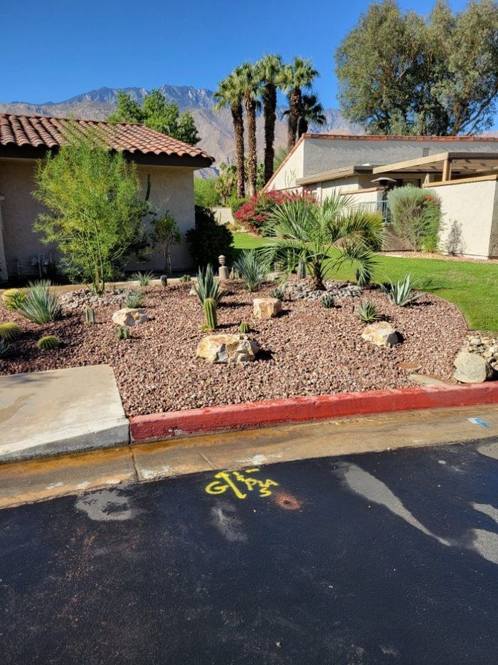 A dirt yard with a brick wall and a house in the background.