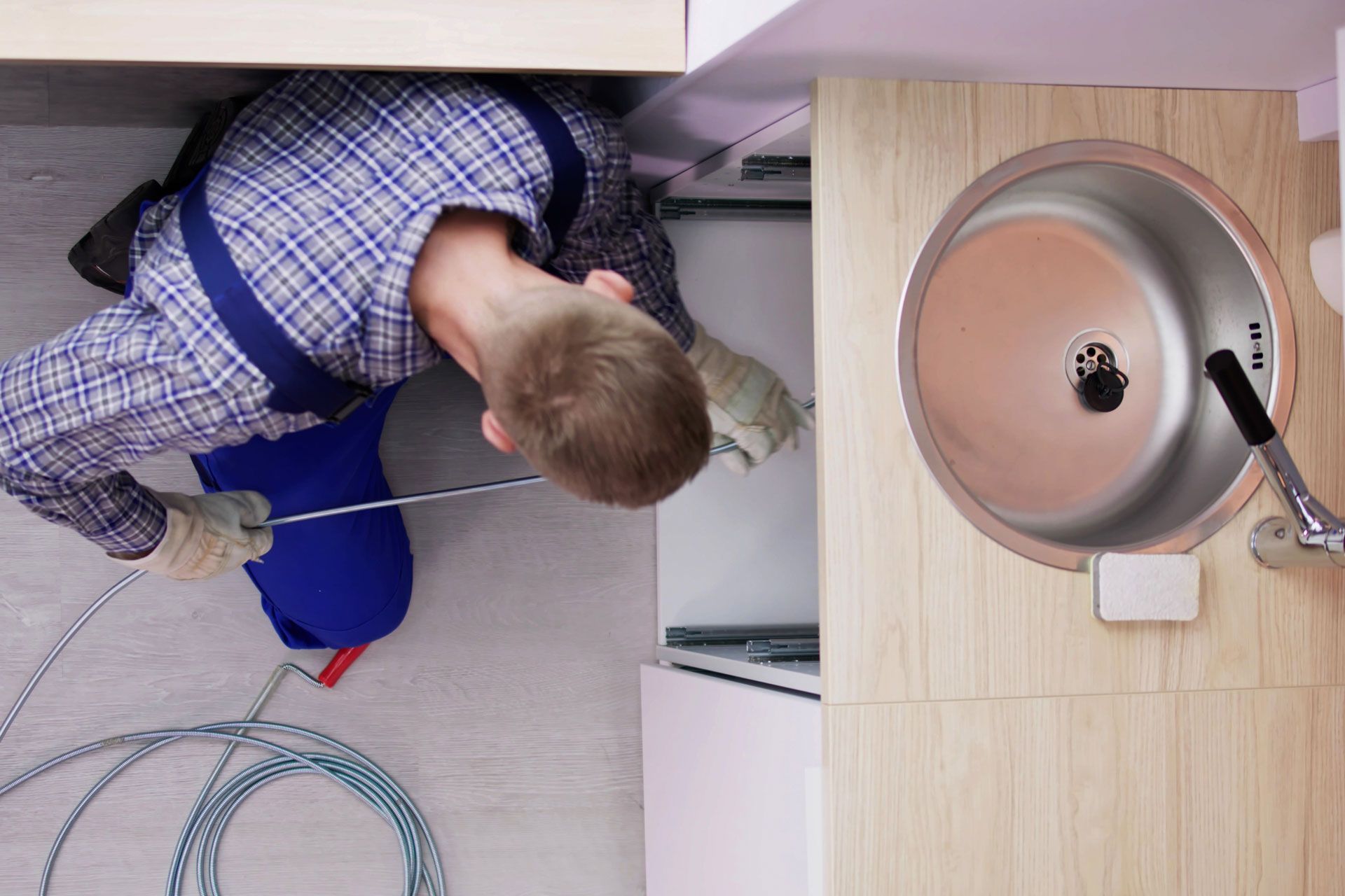 A man is fixing a sink in a kitchen.