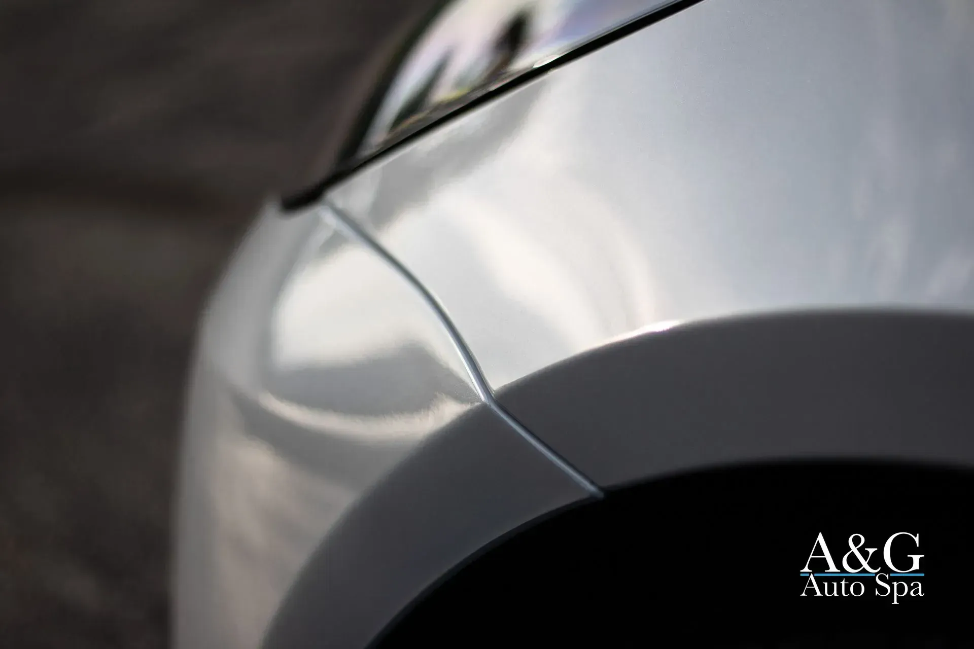 A close up of a car fender with a & g auto spa written on it