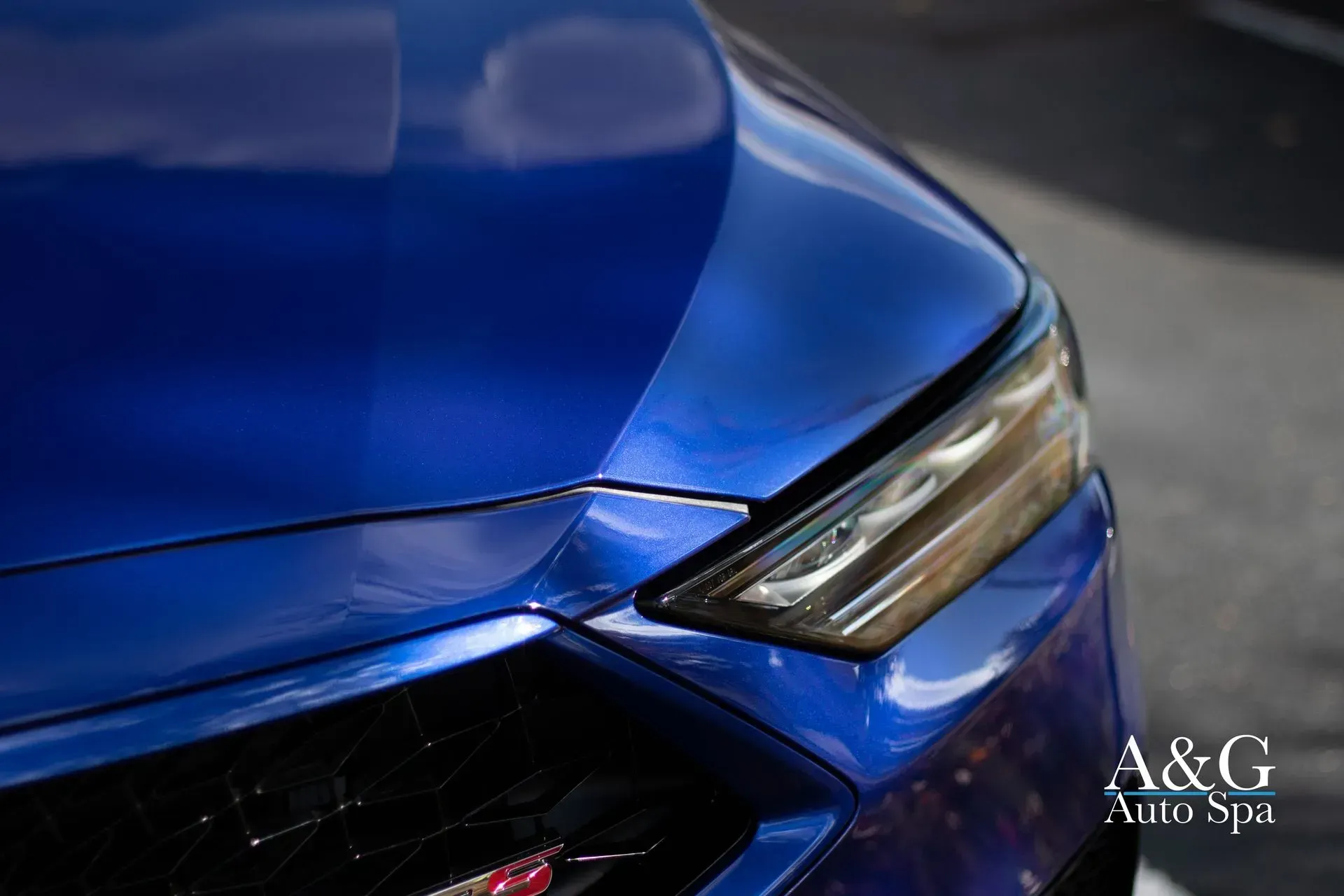 A close up of a blue car 's hood and headlights.