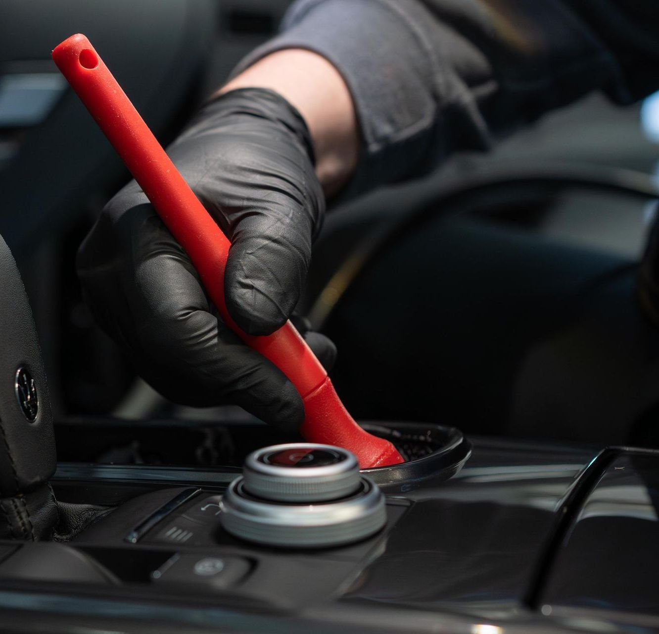 A person wearing black gloves is holding a red brush