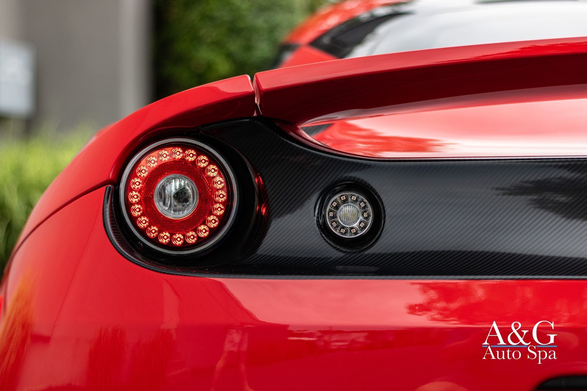 A close up of the tail light of a red sports car.