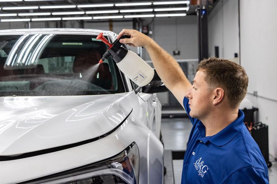 A man is pushing a heavy bag in a garage with cars in the background.