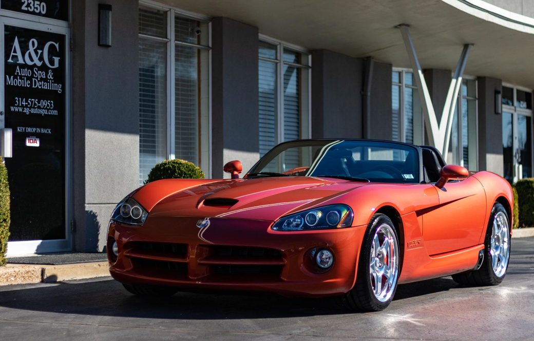 A red dodge viper is parked in front of a building.