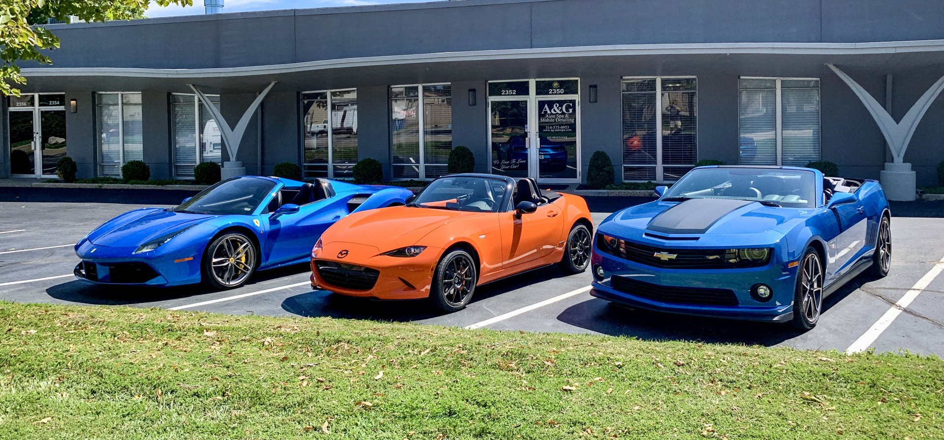 Three sports cars are parked in a parking lot in front of a building.