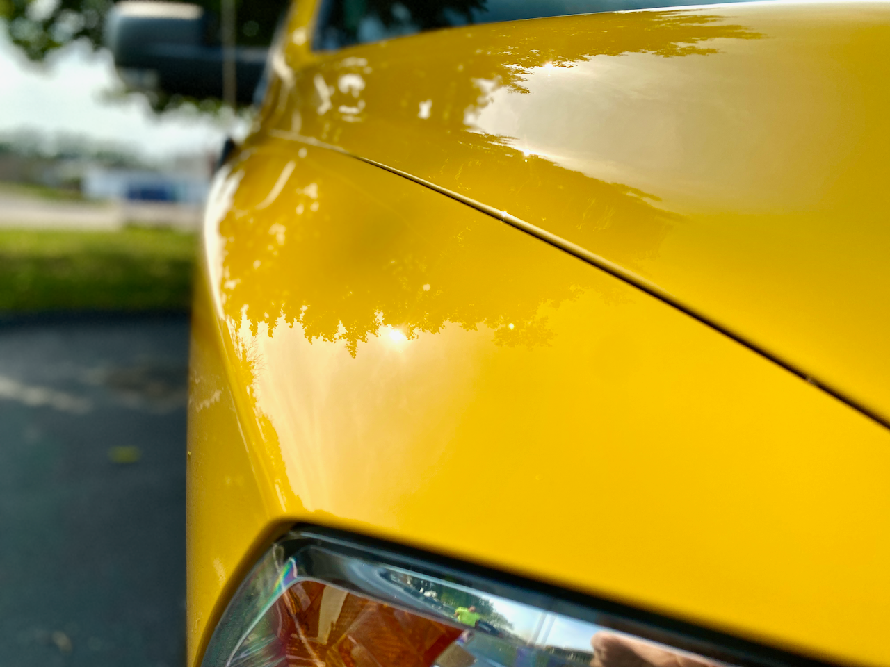 A close up of a yellow car parked on the side of the road.