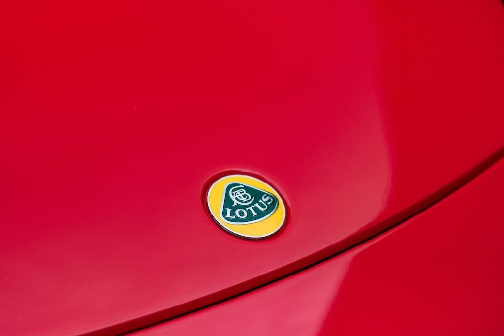 A close up of a lotus logo on the hood of a red car.