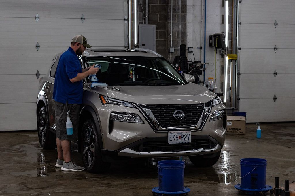 A man is washing a car in a garage.