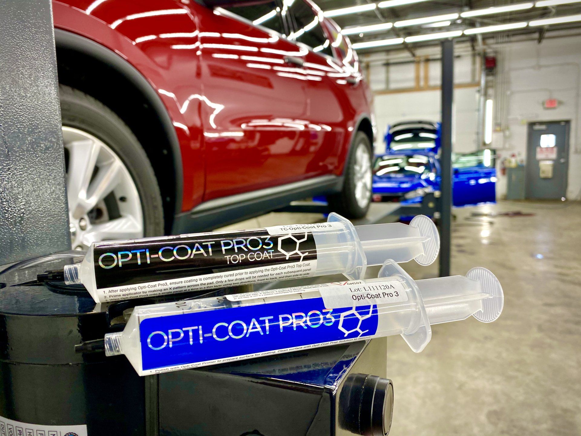 A red car is parked in a garage next to a stack of syringes.