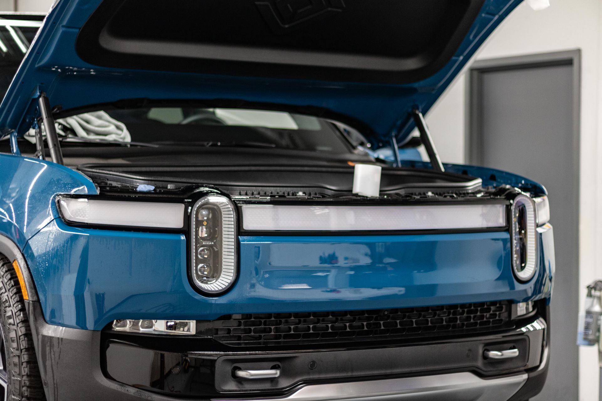 A blue truck with the hood up in a garage.