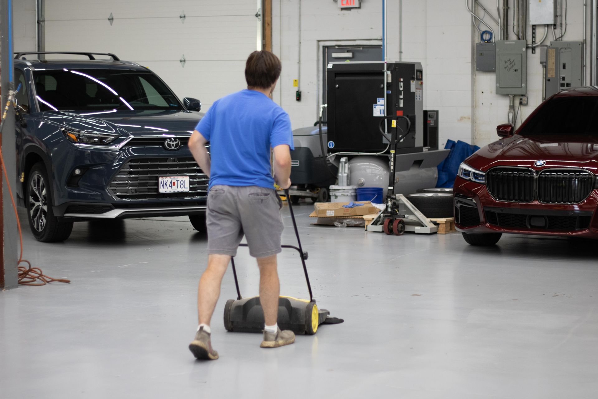 A man is pushing a heavy bag in a garage with cars in the background.