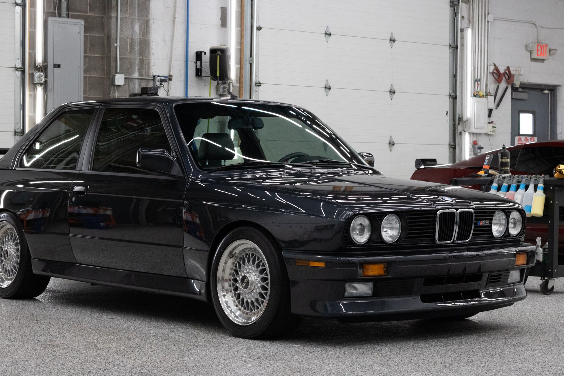 A black bmw m3 is parked in a garage.