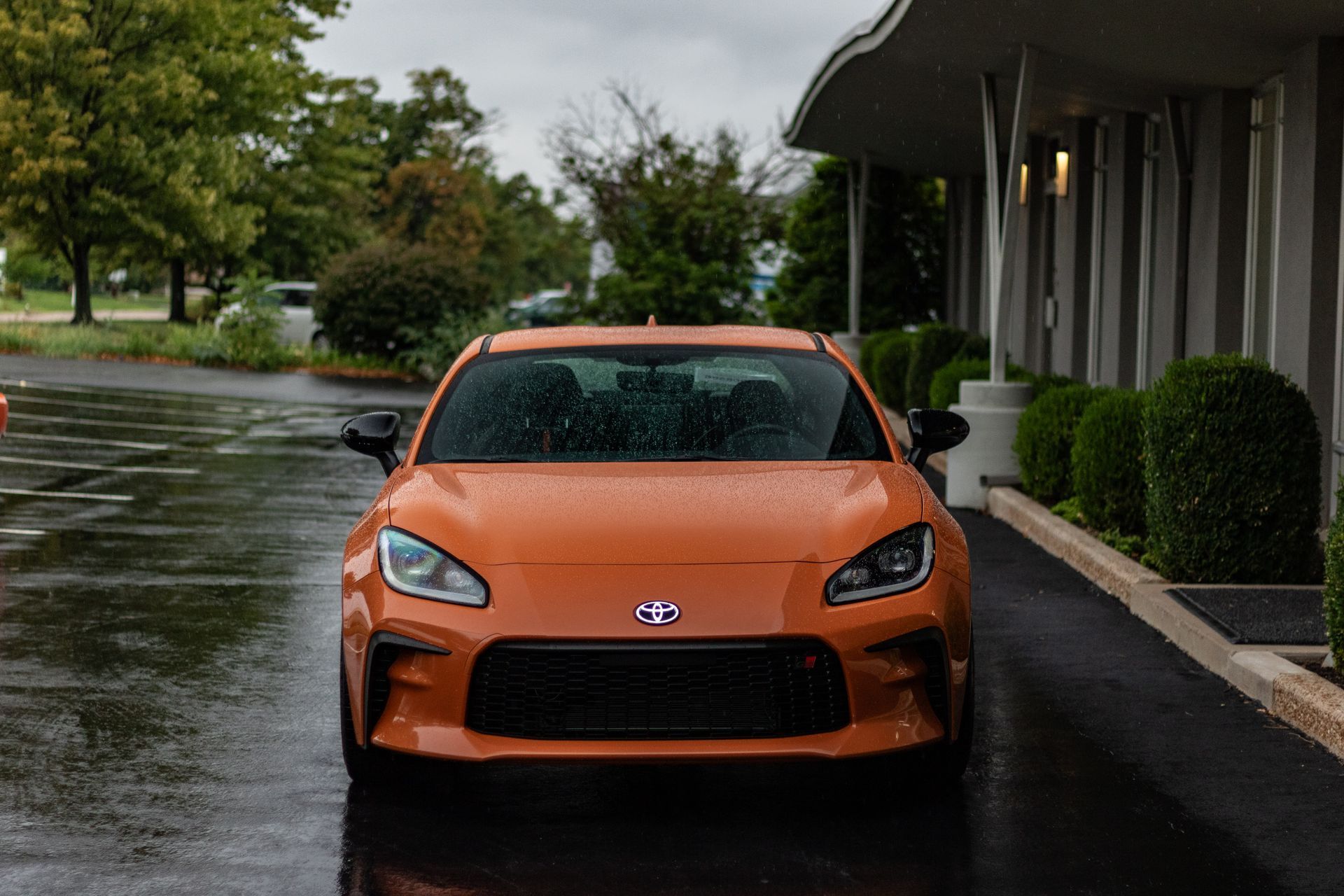 A toyota scion fr s is parked in a parking lot on a rainy day.