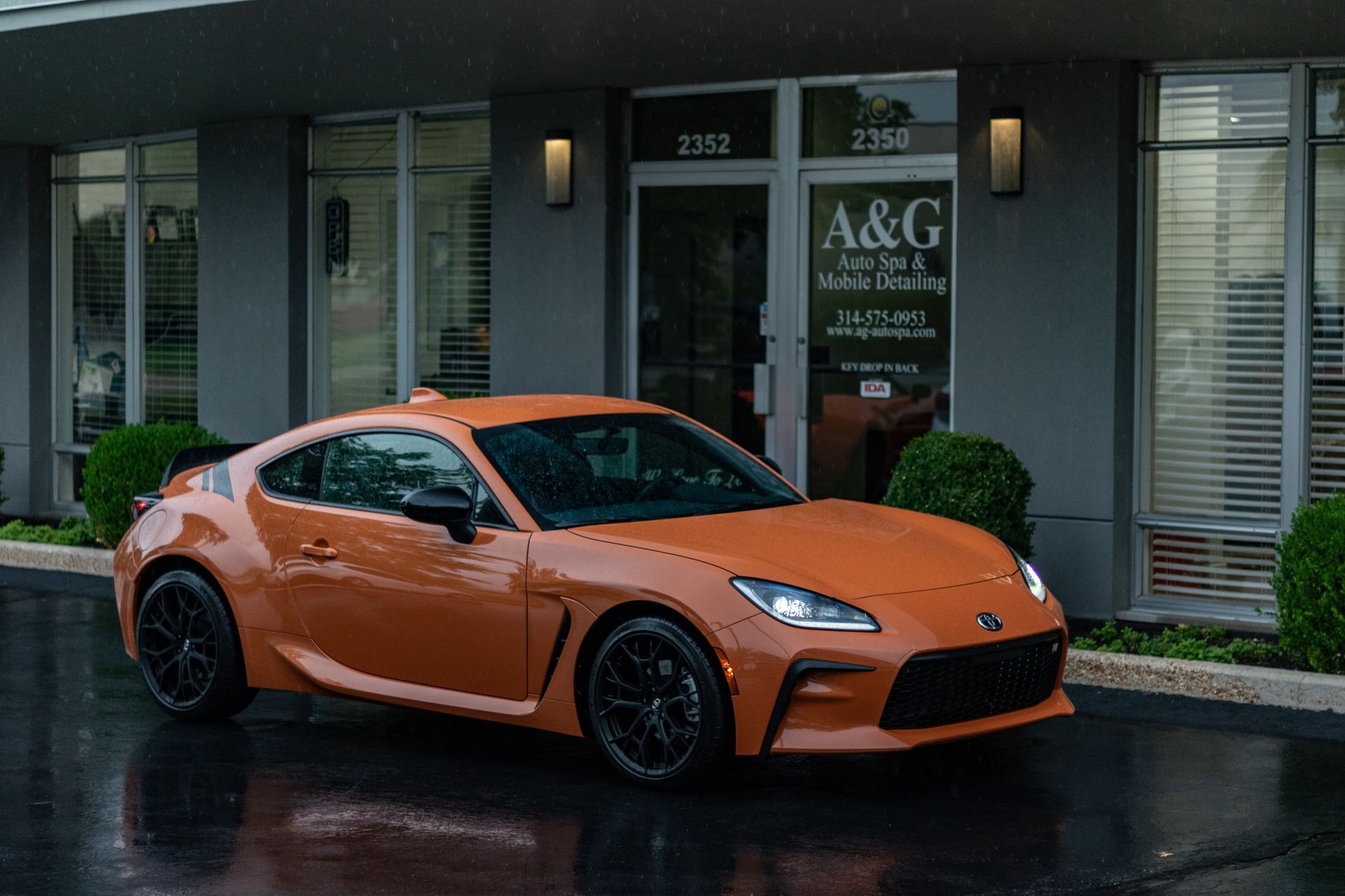 An orange sports car is parked in front of a building.