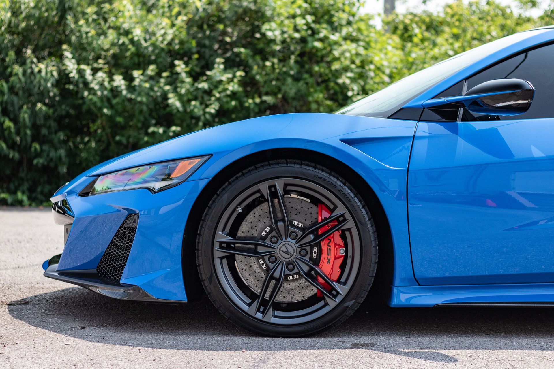 A blue sports car with red brake calipers is parked on the side of the road.