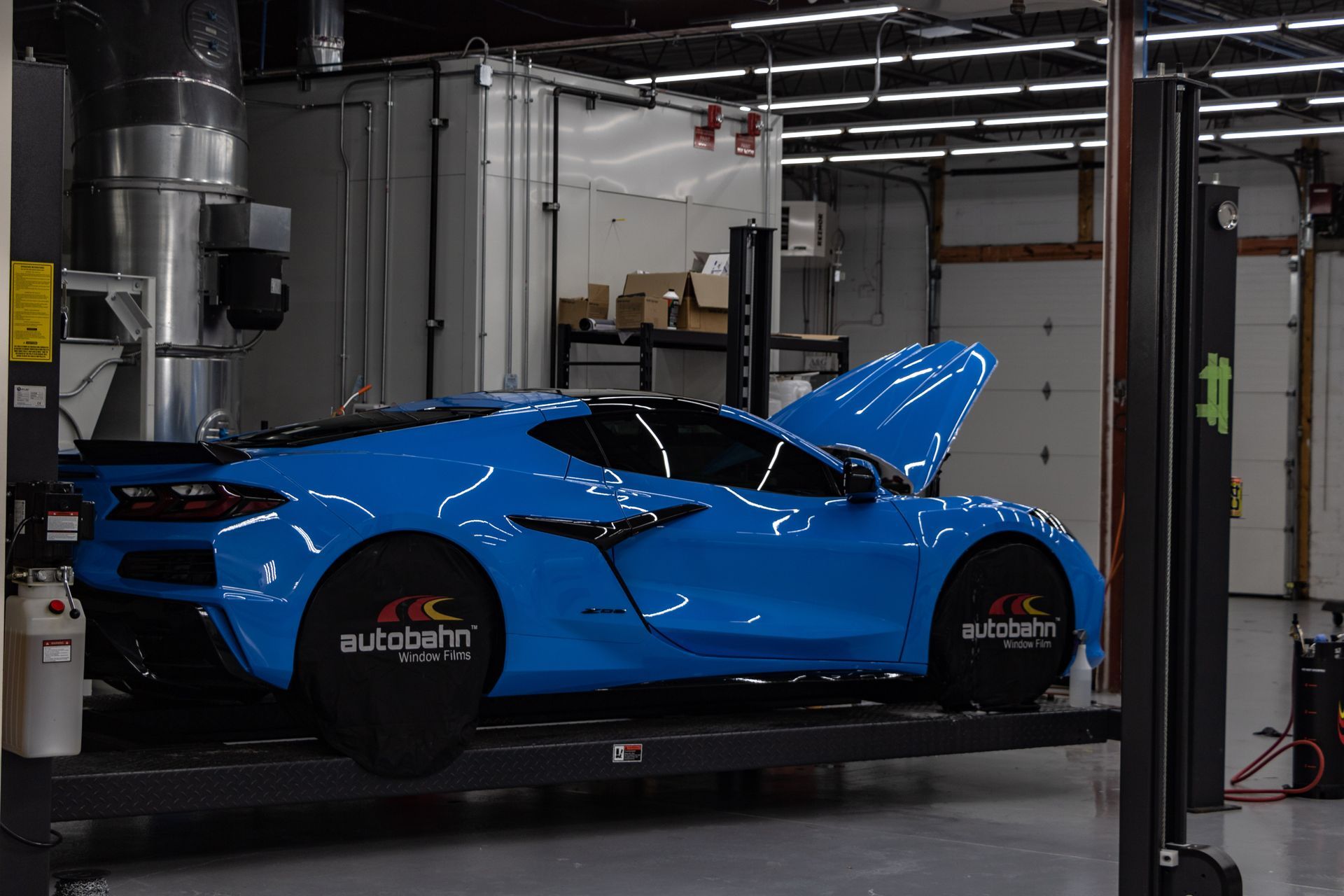 A blue sports car is parked in a garage with its hood open.