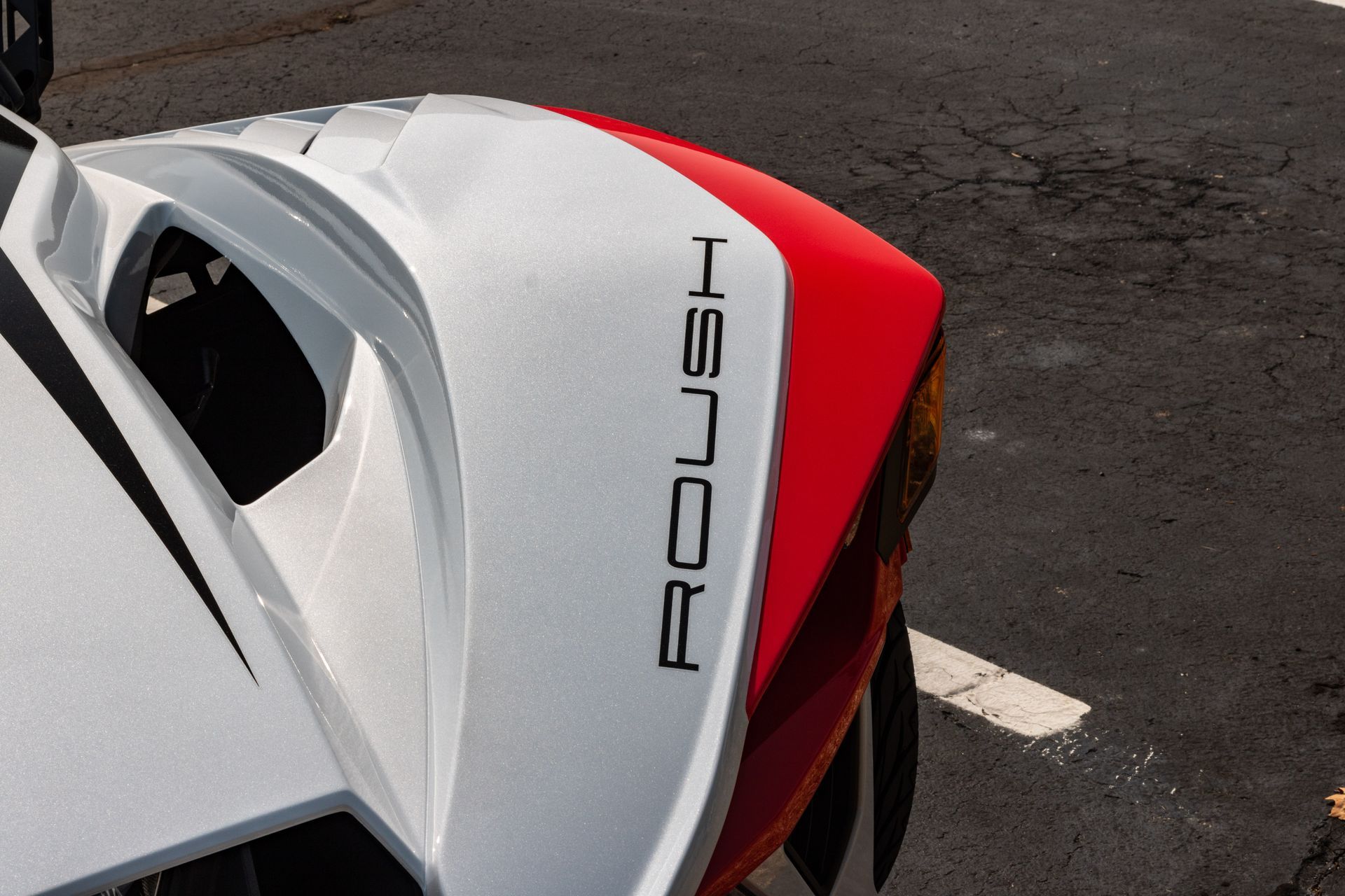 A red and white roush car is parked on the side of the road