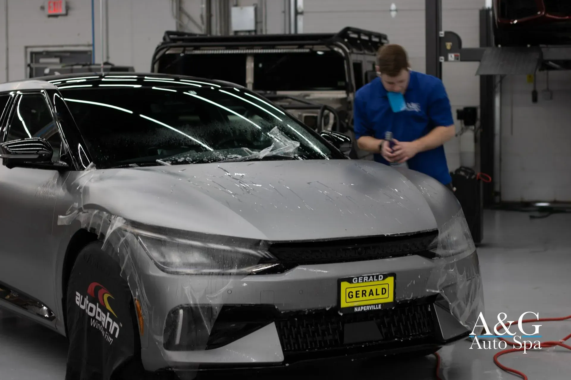A man is wrapping a car in plastic in a garage.