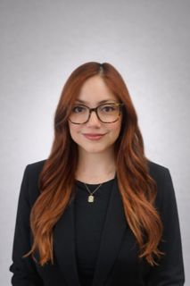 A woman with long black hair is wearing a black jacket and smiling.