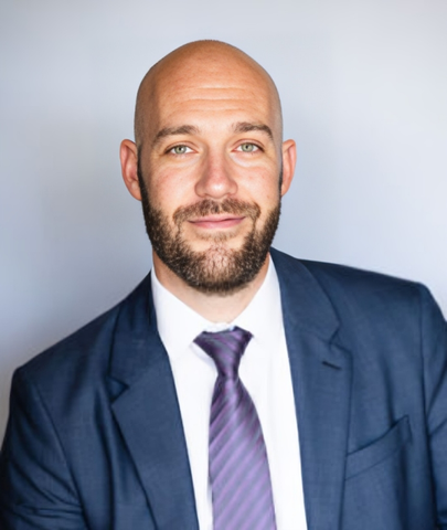 A bald man with a beard wearing a suit and tie