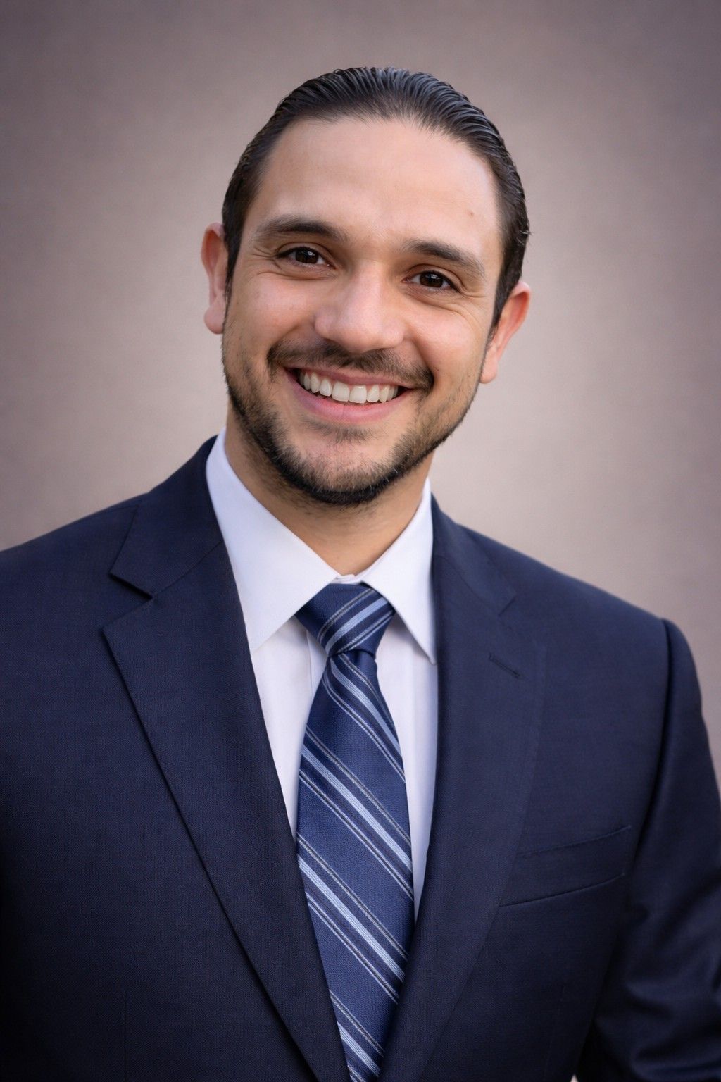 A woman with long black hair is wearing a black jacket and smiling.