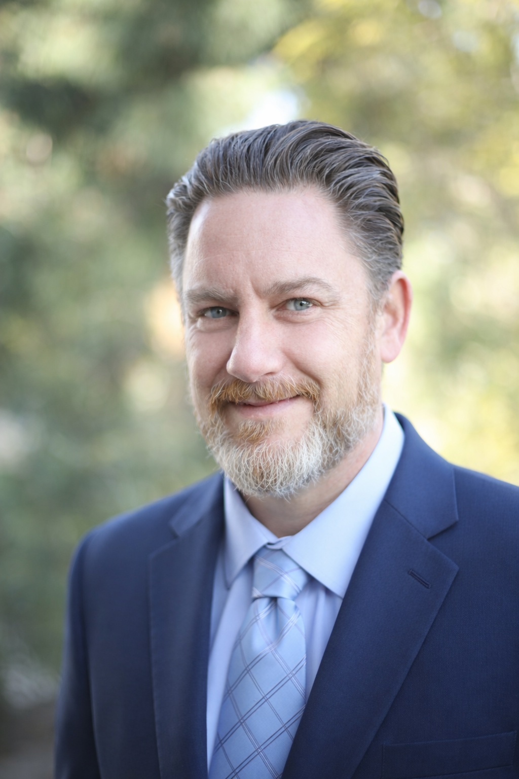 A bald man with a beard wearing a suit and tie