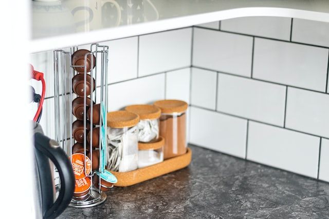 A kitchen counter with a coffee pod holder and a kettle.