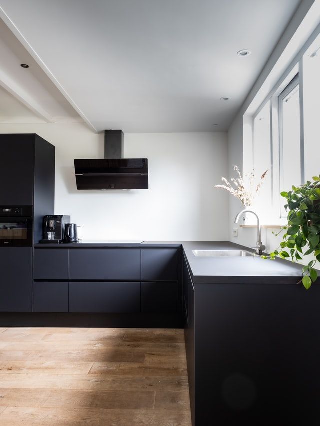 A kitchen with black cabinets , a sink , and a window.