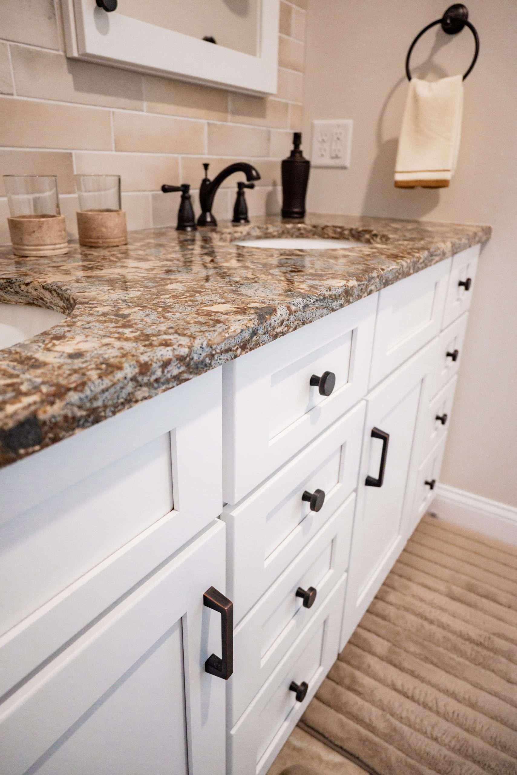 A bathroom sink with a granite counter top and white cabinets.